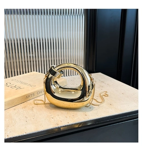 Close-up of polished gold crescent bag with smooth metallic finish and snake chain