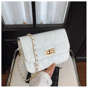 Détail d'un sac à bandoulière matelassé blanc avec fermoir tournant doré et bandoulière chaîne