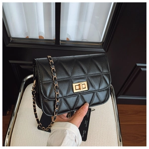 Détail du sac à bandoulière matelassé noir avec fermoir doré et bandoulière chaîne