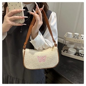 Détail d'un sac sous les aisselles tissé avec broderie papillon rose et garniture en cuir brun
