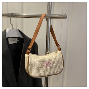 Détail du sac sous le bras en paille classique avec broderie papillon rose et bordure en cuir