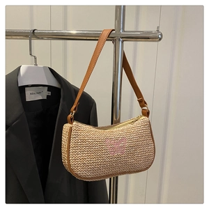 Détail du sac bandoulière en paille avec broderie papillon rose et lanière en cuir