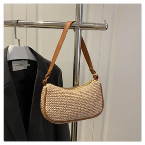 Détail d'un sac d'été en paille avec bordure en cuir marron sur un support métal