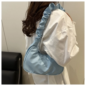 Detail of light blue crescent bag featuring a stylish pleated ruched shoulder strap