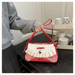 Close-up of red plaid bag featuring cream ruffles, black heart print, and bow detail