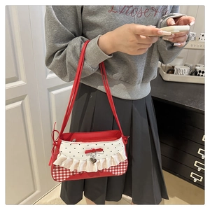 Close-up of a red and white checkered shoulder bag with bow and heart pendants