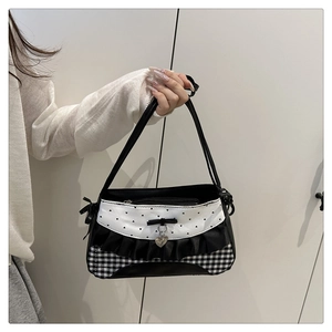 Detail showing lace ruffles, checkered patterns, and heart pendant on the shoulder bag