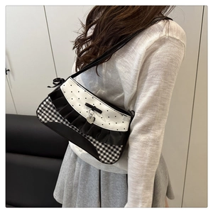 Detail of gingham shoulder bag featuring black lace trim and a silver heart pendant