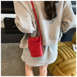 Modern red pebbled leather bucket bag styled on a model in a minimalist interior setting