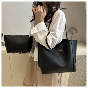 Detail of minimalist black leather tote bag with matching zippered pouch and fashion logo