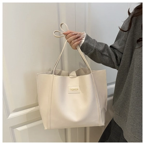 Detail view of large cream leather tote bag with FASHION label and double handles