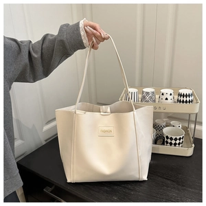 Detail of cream white tote bag featuring long straps and a minimalist Fashion leather patch