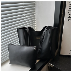 Detail of matte black tote and pouch set featuring gold lettering and shadow lighting