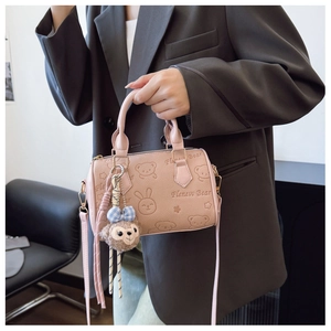 Close-up of pink embossed cartoon Boston bag featuring cute bear pattern and plush charm