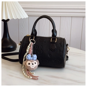 Macro detail of black embossed pillow bag featuring cartoon bear patterns and plush charm