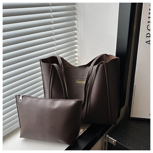 Close-up of a deep coffee leather tote bag and matching clutch with FASHION label detail