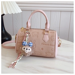 Detail of pink embossed bear pattern handbag with plush charm and gold hardware