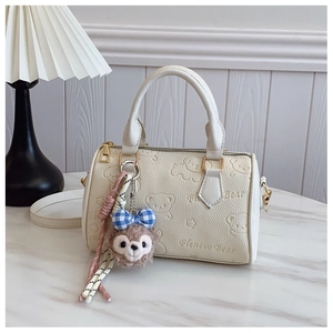 Detail of embossed bear pattern on beige Boston bag with plush character charm