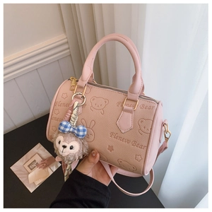 Close-up of pink faux leather bag with embossed bear pattern and plush bear charm