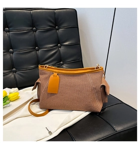 Detail der gewebten Handtasche mit orangefarbenem Lederbesatz auf schwarzem Stuhl