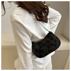 Detail of black half-moon shoulder bag with floral embossing and silver chain strap