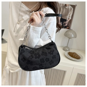 Close-up of black jacquard chain bag with floral pattern shown on a shoulder