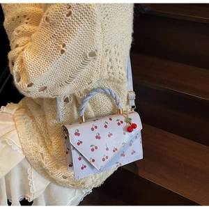 Détail d'un sac bandoulière pour femme avec imprimé cerise et poignée tressée