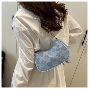 Detail of light blue crescent bag with floral jacquard texture and silver chain strap
