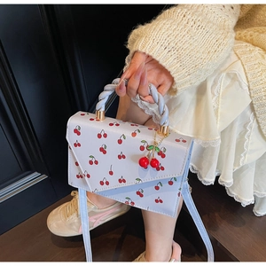 Detail of light blue cherry print handbag with twisted handle and fruit charm