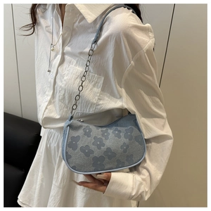 Detail of light blue floral jacquard fabric and silver chain strap on underarm bag