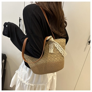 Detail of hand-woven straw tote bag with delicate lace bow and brown faux leather straps