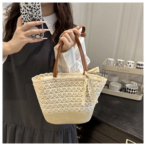 Detail of hand-woven straw tote with elegant white lace crochet and brown leather handles