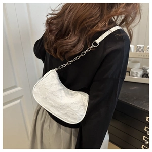 Close-up of white floral embossed hobo bag with chain strap on model shoulder