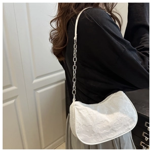 Detailed view of white floral embossed chain shoulder bag with metallic strap on model