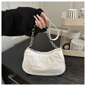 Detailed view of white fabric handbag with textured 3D floral pattern and chain strap