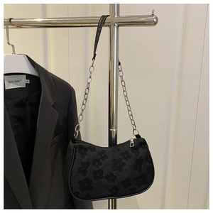 Detail of black floral jacquard underarm bag with metal chain strap and silver zipper