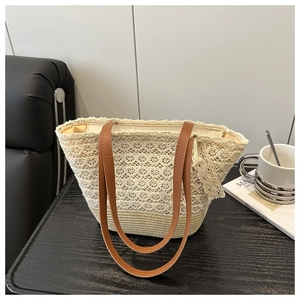 Detailed shot of beige lace tote bag with straw base and brown leather straps