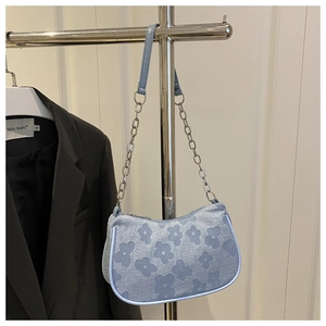 Detail of light blue underarm bag with 3D floral jacquard texture and chain strap