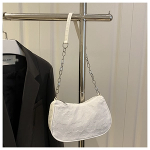 Close-up of white floral jacquard texture and silver chain strap on this shoulder bag