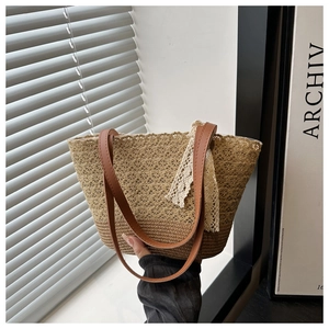 Close-up of woven straw tote bag with brown leather handles and delicate white lace ribbon