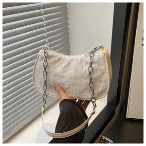 Detail of white textured floral jacquard fabric on a chic baguette handbag with chain