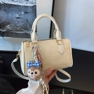 Creamy leather cylinder bag with embossed bear pattern and plush keychain accessory