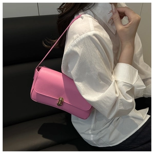 Detail of pink faux leather shoulder bag featuring a gold twist lock on the front flap
