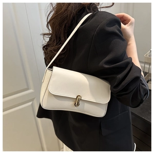 Close-up of a white minimalist shoulder bag with a sleek gold capsule-shaped metal buckle