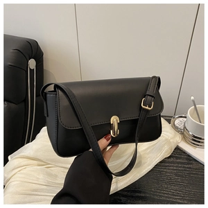 Detail of minimalist black matte leather square bag with polished gold cylinder clasp