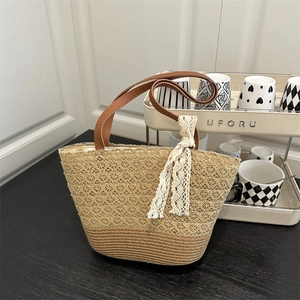 Summer straw tote bag with brown base and elegant lace ribbon on a wooden surface
