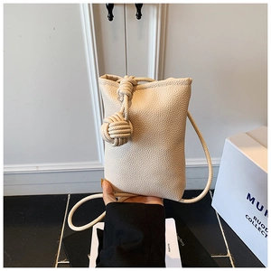 Detail of cream mini crossbody bag with lychee texture and decorative rope knot