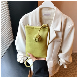Detailed macro view of lime green textured leather crossbody bag with knot strap