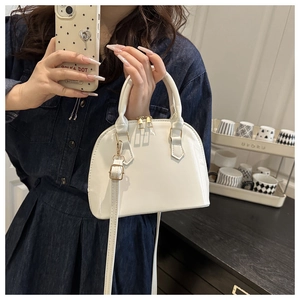 Detail of white glossy patent leather shell bag with gold zippers and dual-use strap