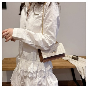 Détail du sac à bandoulière en patchwork tressé avec cuir et chaîne dorée